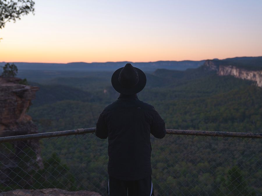 A walker in an Akubra watching sunset over the gorge from Boolimba Bluff Lookout