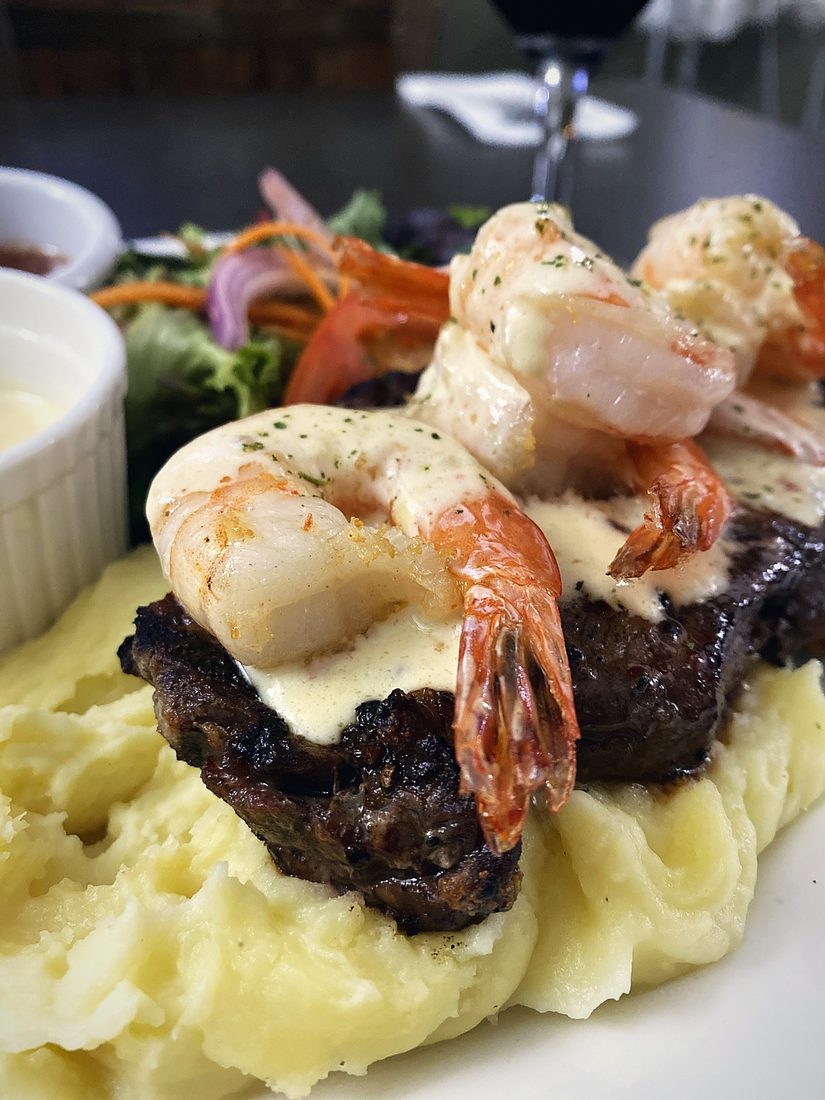 Steak topped with garlic prawns on creamy mash