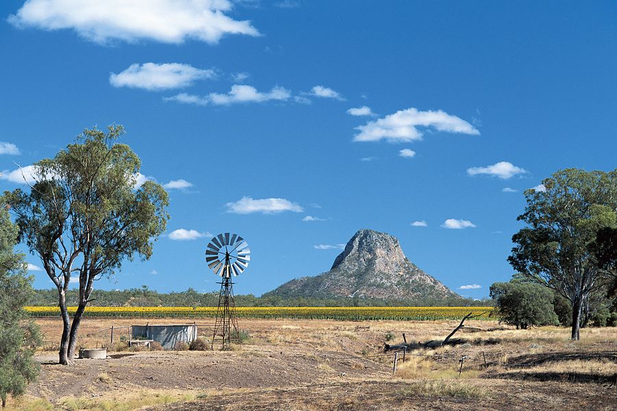 A windmill & farmland beneath a rocky peak near Springsure